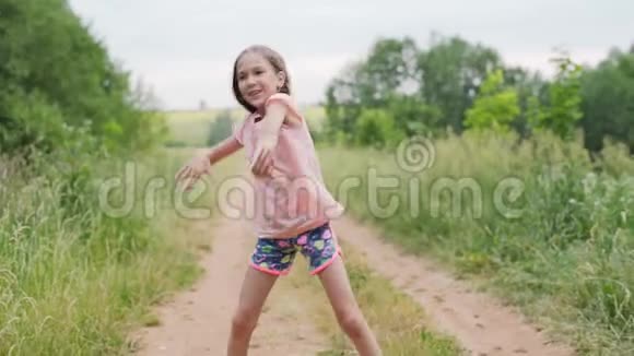 欢快的女孩在乡间的路上跳舞夏日小女孩在露天表演不同的舞蹈动作视频的预览图