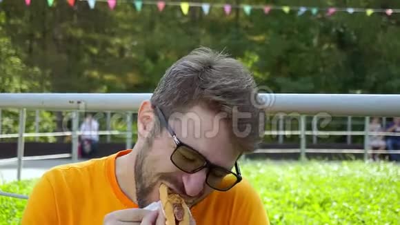 一个戴着眼镜和胡子的中年男人吃热狗特写视频的预览图