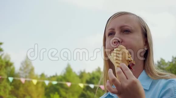 中年妇女在街上吃热狗天空的特写视频的预览图