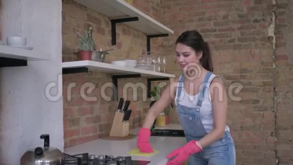 戴着橡胶手套的微笑主妇在厨房和家务中的画像视频的预览图