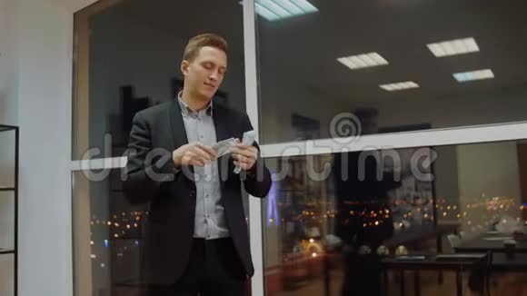 有钱的商人从办公室的橱窗里扔钱视频的预览图