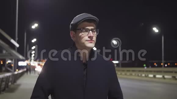 晚上一个年轻优雅的男人沿着高速公路走在人行道上视频的预览图