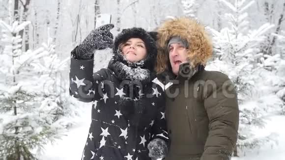 年轻的幸福夫妇是在雪地森林里拍摄的自拍冬季旅行概念视频的预览图