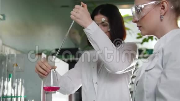 化学实验室两个年轻的女人在做实验瓶中的红色液体视频的预览图