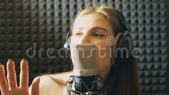 在录音室唱歌的漂亮女孩的肖像年轻歌手有感情地录制新歌女士唱歌视频的预览图