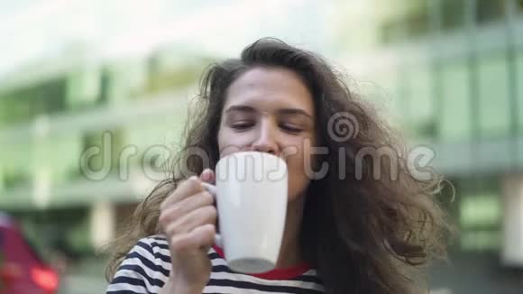 年轻漂亮的黑发女郎在夏天的咖啡馆里享受咖啡微笑着视频的预览图