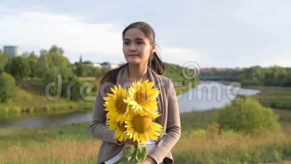 年轻快乐的亚洲女人一边拿着向日葵一边思考一边放松的自然景观视频的预览图