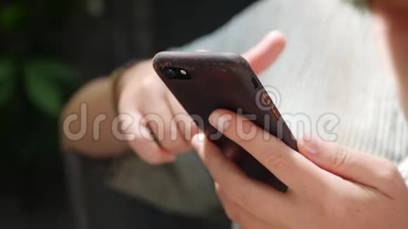 一个女人坐在咖啡馆里使用智能手机的手的特写女孩使用移动应用程序视频的预览图