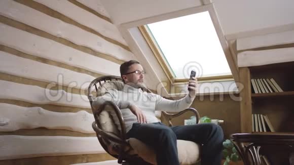 戴眼镜的成年男子在智能手机的网上交流视频的预览图