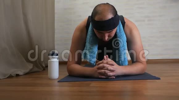 有趣的胖子在瑜伽垫上厌倦了上课用水冷却自己视频的预览图