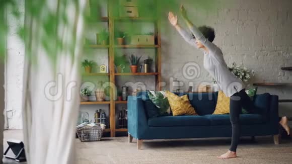 活跃的人在家里做瑜伽单独站在地板上练习单腿平衡练习漂亮的阁楼视频的预览图