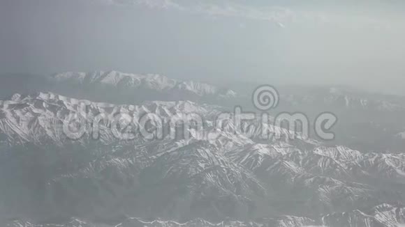 鸟瞰雪山云海从飞机上看山上的褶皱山顶覆盖着视频的预览图