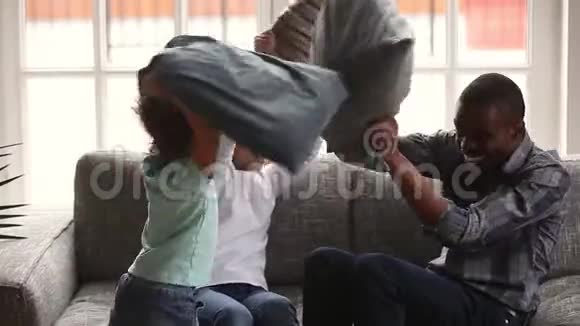 快乐的非洲家庭爸爸和小孩享受枕头大战视频的预览图