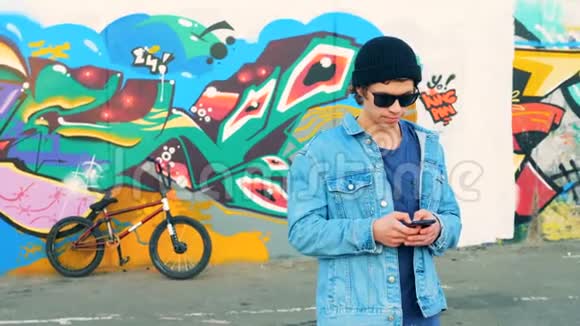 年轻时尚的白人男性青少年在智能手机上的自行车背景近距离视频的预览图