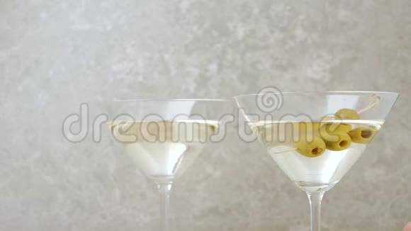 豪华马提尼手从桌上拿一杯马提尼上面装饰着橄榄鸡尾酒棒石灰和薄荷视频的预览图