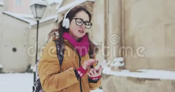 冬天女人在城市里用手机听音乐漂亮的年轻女子穿着听音乐视频的预览图