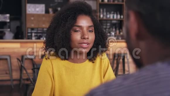微笑的年轻女子在咖啡馆里和男人说话视频的预览图
