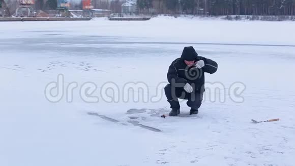 穿着深色冬装的渔夫们用鱼饵准备钓钩并准备在冰冻的河流上进行冬季冰钓视频的预览图