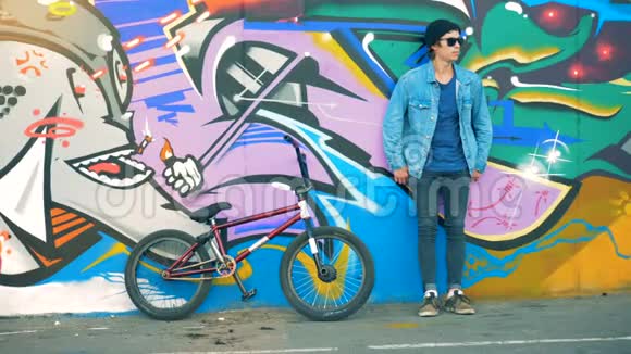 骑自行车的人靠在彩色的墙上年轻时尚的白人男性青少年视频的预览图