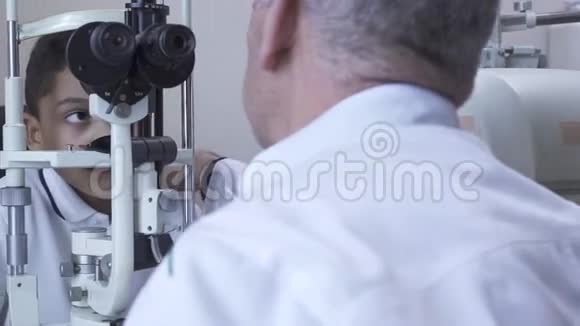 小帅哥在诊所做眼科检查坐在医生面前穿着白色的医用外套看着验眼机视频的预览图