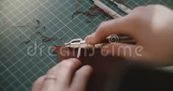 特写镜头的女性手工作切割边缘的小块皮革在一个特殊的桌子上与专业的工具视频的预览图