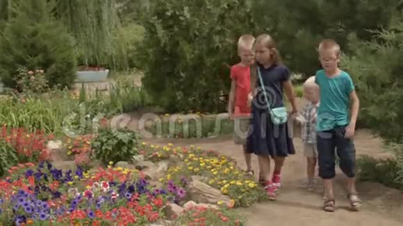 孩子们回到学校暑假后新学年开始带着书包的男孩和女孩在花丛中玩耍视频的预览图