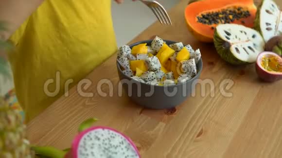一个穿着黄色衬衫的小男孩在桌上吃芒果龙果和许多热带水果视频的预览图