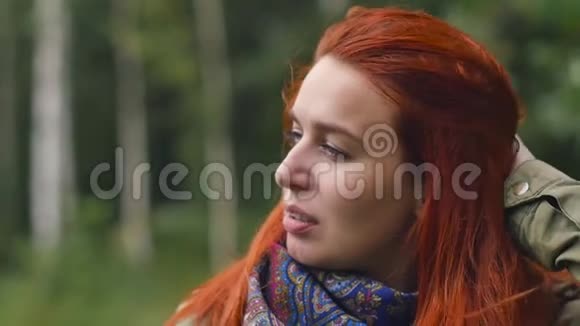一位年轻的红发女子呼吸着干净的空气在秋天的森林里散步慢动作视频的预览图