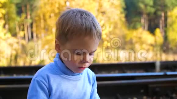 男孩坐在铁轨上吃一个面包秋天温暖的一天视频的预览图