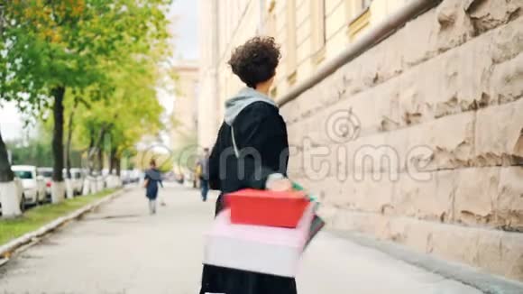 慢镜头肖像兴奋女孩拿着礼品袋和旋转看相机乐趣购物青年视频的预览图
