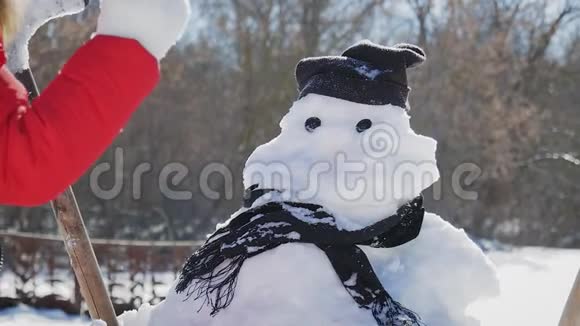 女孩在雪人上插入一个鼻子孩子玩雪人冬天的快乐时光雪上的孩子视频的预览图