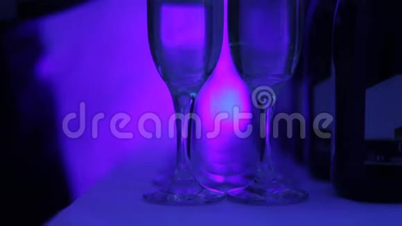 香槟酒杯站在桌子上一排在聚会上用多种颜色的光线突出视频的预览图