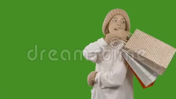 一个快乐的女孩在一个孤立的绿色背景下购物后带着纸袋的肖像视频的预览图