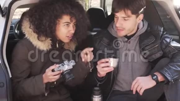两人在汽车后备箱里一边喝咖啡一边拍照视频的预览图
