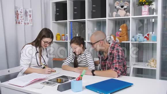 4友好的医生在办公室里和父亲和孩子的病人交谈视频的预览图