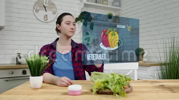 布鲁内特漂亮的女人在厨房使用透明全息未来屏幕购买蔬菜在线未来视频的预览图