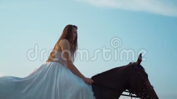 夕阳西下一个留着长发穿着白色连衣裙骑着马走过水面的漂亮女孩视频的预览图