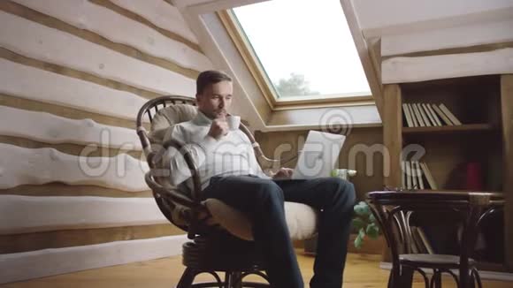 戴手提电脑的胡子男人在阁楼上喝咖啡视频的预览图