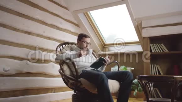 戴眼镜的漂亮胡子男看书在阁楼上喝咖啡视频的预览图