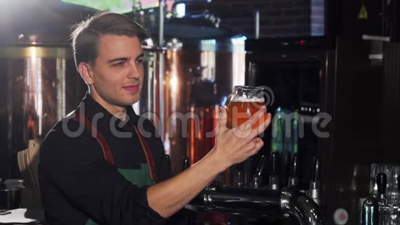 开朗的酒保看着杯子里的啤酒在他的工艺啤酒酒吧工作视频的预览图