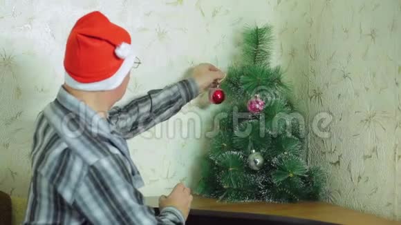 一个戴圣诞老人帽子的人用节日气球装饰圣诞树视频的预览图