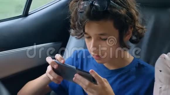 小男孩开车旅行时用电话视频的预览图