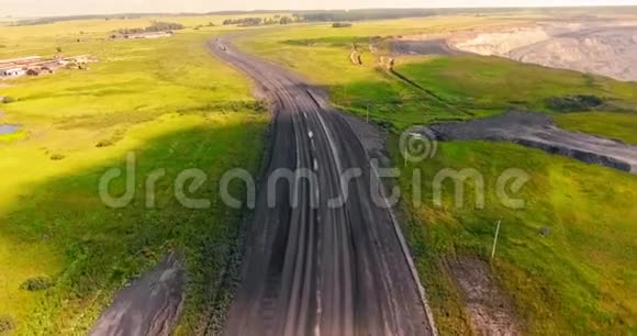 卡车的航空测量倾斜覆盖的自卸汽车沿着乡村道路运输煤炭卡车在肮脏的乡村行驶视频的预览图