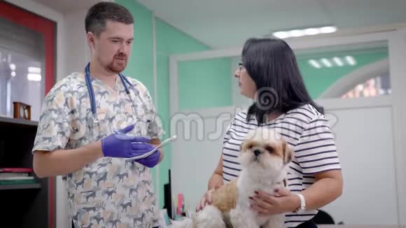 专业兽医与狗主人在诊所检查后交谈医生与客户和她的宠物视频的预览图