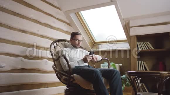 成年男子在阁楼上的智能手机上通过社交网络发短信视频的预览图