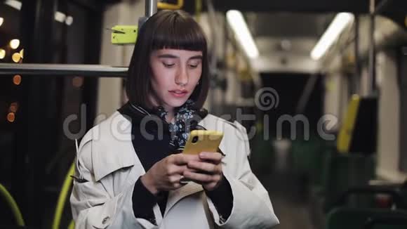 幸福的年轻女人在公共交通中使用智能手机的肖像城市灯光背景视频的预览图