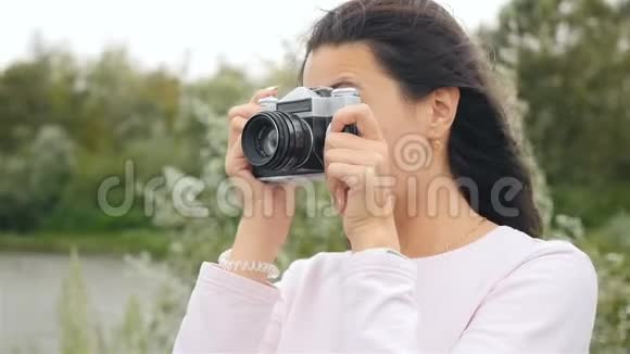 美丽的女孩在复古相机上拍照慢动作特写视频的预览图