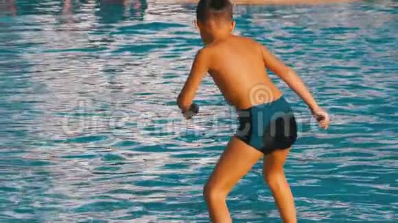 快乐男孩跳进蓝水池慢动作视频的预览图