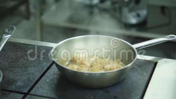 特写放在灶台上的平底锅锅肉都炒了油沸腾蒸汽从平底锅中升起视频的预览图