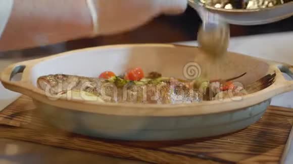 厨师双手戴白色橡胶手套将切好的蔬菜放入橄榄油中放在煮熟的鱼上食品准备视频的预览图